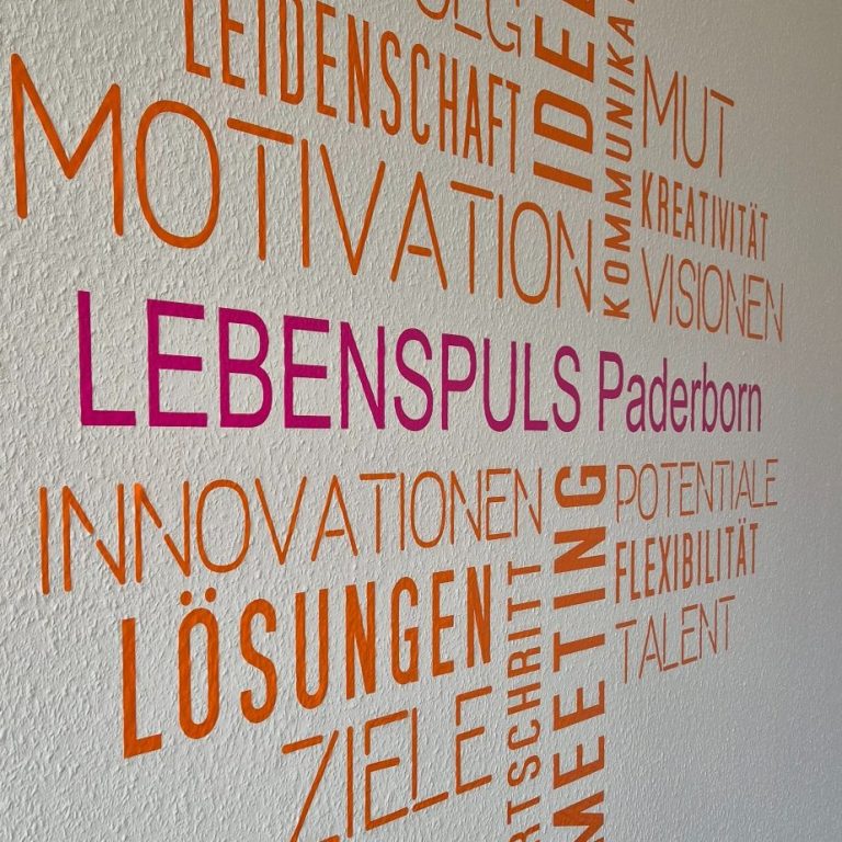 Wandgestaltung mit bunten Wörtern zu Motivation, Innovation und Zielen von Lebenspuls Paderborn.