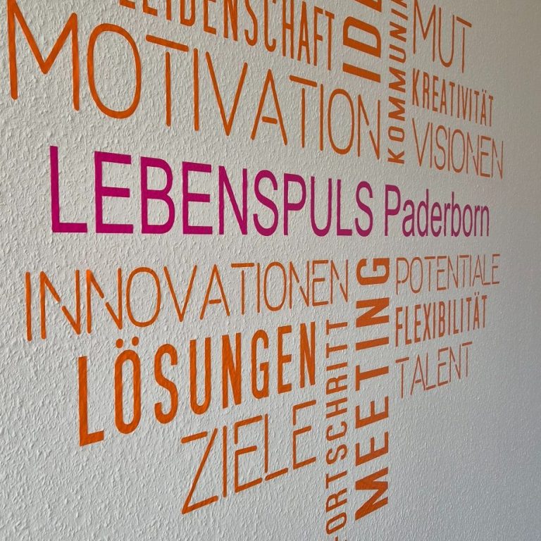 Wandgestaltung mit bunten Wörtern zu Motivation, Innovation und Zielen von Lebenspuls Paderborn.